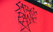 A red overhead screen with scrawled Satanic Panic text over a star. Copyright: 2021 Cassiano Rosario